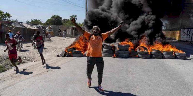 Seorang demonstran berdiri di depan ban yang sengaja dibakar dalam aksi unjuk rasa yang dilakukan polisi Haiti, di Port-au-Prince pada Kamis, 26 Januari 2023/Net