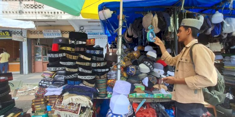 Seorang warga mencoba pakai peci di lapak dagangan Agus di kawasan Pasar Aceh atau tepatnya di belakang Masjid Raya Baiturrahman, Banda Aceh/RMOLAceh