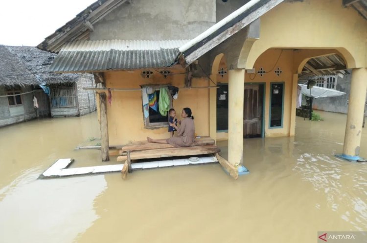 ilustrasi - Warga berada di depan rumahnya yang terandam banjir di Desa Idaman, Pandeglang, Banten, Kamis (5/12/2024). (ANTARA/Bagus Khoirunas)